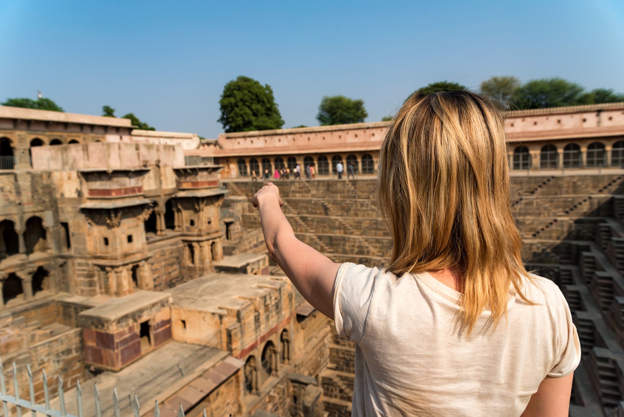 A Girl Traveler Pointing To Famous Stepwell Chand Baori.